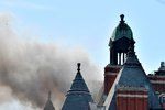 Více než stovka hasičů bojuje s požárem luxusního hotelu v centru Londýna. Ze střechy budovy stoupá hustý dým.