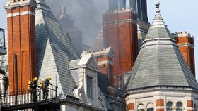 Více než stovka hasičů bojuje s požárem luxusního hotelu v centru Londýna. Ze střechy budovy stoupá hustý dým.