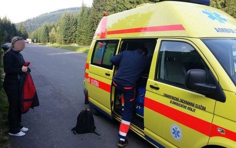 Šťastná dcera zachráněné ženy u sanitky, v níž lékaři pečují o její maminku vytaženou z rašeliny.