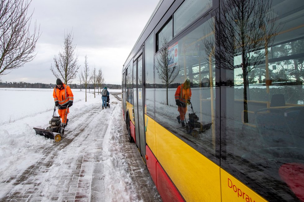 Pracovník technických služeb v Hradci Králové odklízí sníh z autobusové zastávky (13. 1. 2020)