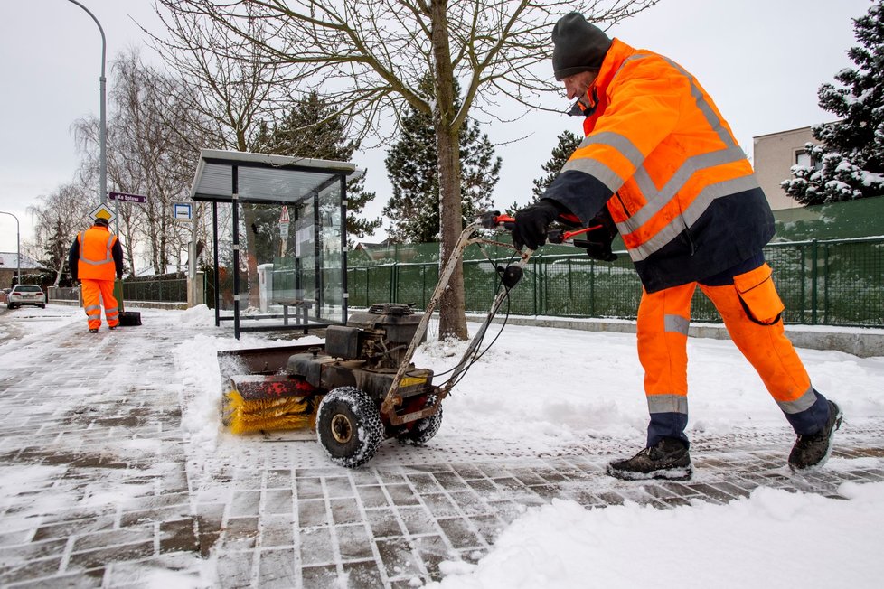 Pracovníci technických služeb v Hradci Králové odklízejí sníh z autobusové zastávky (13. 1. 2020)