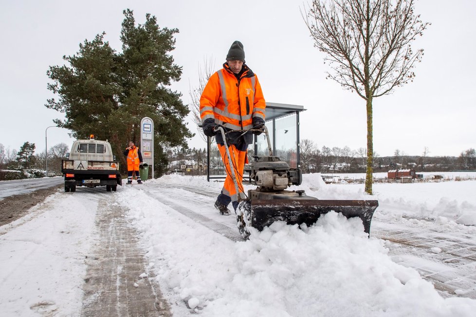 Pracovník technických služeb v Hradci Králové pomocí frézy odklízí sníh z autobusové zastávky (13. 1. 2020)