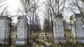 Za těžkou železnou bránou se prostředkem hřbitova vine široká cesta.