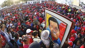 Muž drží v tisícihlavém davu obraz Cháveze