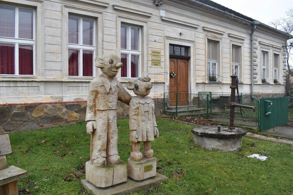 Bývalá škola v Mladějovicích, před ní stojí socha Spejbla a Hurvínka.