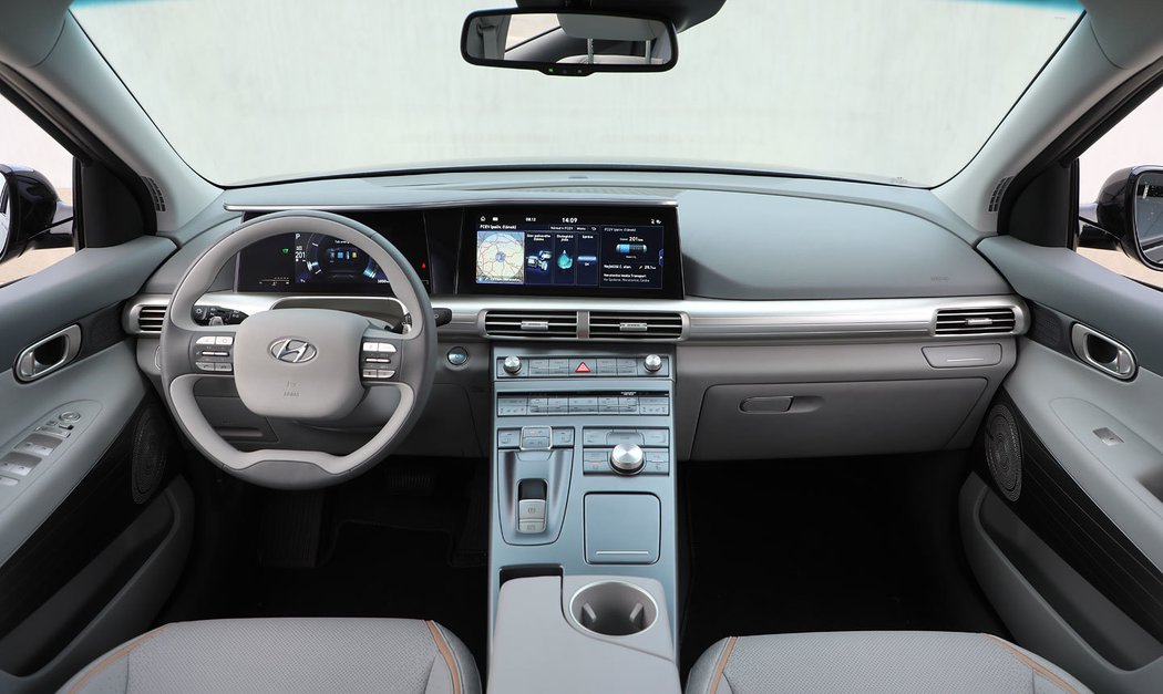 Takovéto tvary interiéru jsou pro Hyundai nezvyklé. Dvouramenný volant s hranatým středem, dva displeje spojené dohromady společným krytím a jednoduché linie. Zpracování i materiály jsou na špičkové úrovni, i když zvolená barevná kombinace nepatří k nejpohlednějším.