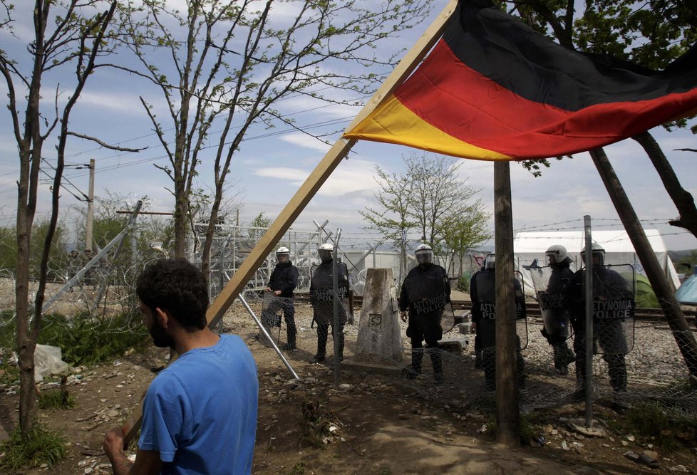 Uprchlík v Idomeni na řecko-makedonské hranici s německou vlajkou. Migranti se chtějí dostat právě především do Německa.