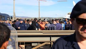 Dav lidí, který se shlukl kolem mrtvého hada, museli rozehnat policisté kvůli projíždějícímu vlaku. Protagonista nadále třímá mrtvolu v rukou.