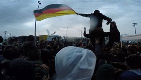 Rozvášnění uprchlíci s německou vlajkou během pondělního protestu v Idomeni.