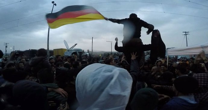 Rozvášnění uprchlíci s německou vlajkou během pondělního protestu v Idomeni