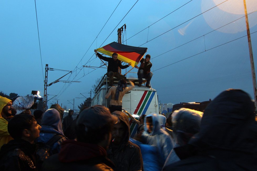 Rozvášnění uprchlíci s německou vlajkou během pondělního protestu v Idomeni