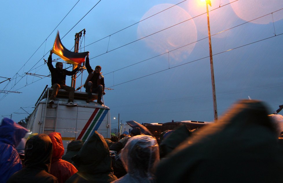 Debata uprchlíků o dalším postupu se ve večerních hodinách proměnila v protest za otevření hranic. Běženci mávali německou vlajkou na znamení, do které země směřují.