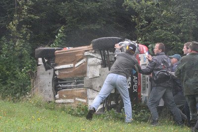 A končí opět na boku. Fanoušci pomáhají, ale vůz je hodně poničený.