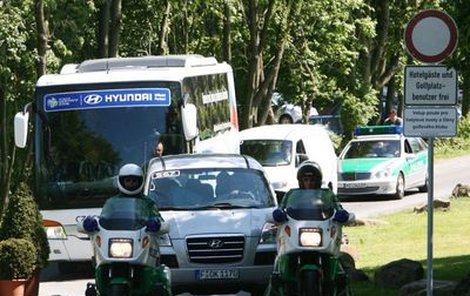 Český autobus obklopen policejními auty a motorkami si razí cestu westerwaldskými lesy k průmyslové zóně okolo Gelsenkirchenu. 