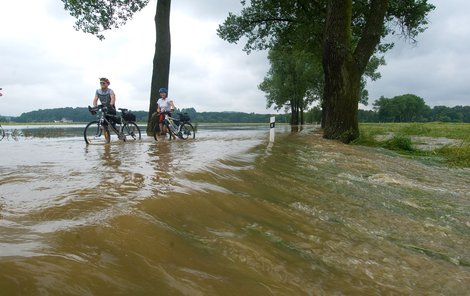 Cyklisté na silnici z Netolic do Bavorova, kterou zaplavila řeka Blanice.