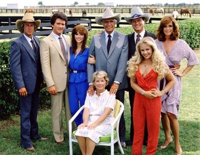 Ewingové v plné síle: zleva Steve Kanaly (63), Patrick Duffy (60), Victoria Principal (59), Jim Davis (†71, zemřel v roce 1981), Larry Hagman (78), Charlene Tilton (50), Linda Gray (69), v křesle Barbara Bel Geddes (†82, zemřela v roce 2005).