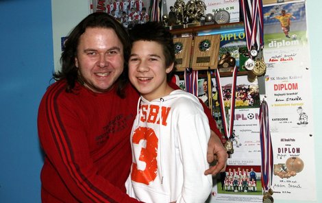 Jiří Staněk se svým synem pózuje před trofejemi z fotbalových zápasů Slavie.