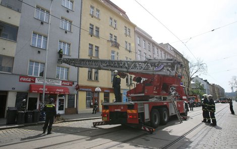 K oknu bytu v pražských Holešovicích vysunuli hasiči dlouhý žebřík. Zatarasili při tom průjezd autům i tramvajím.