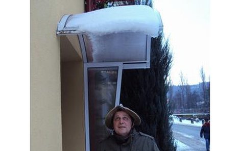 Petr Dvořák si před padajícím sněhem chrání hlavu přilbou.