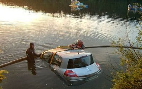 Potápěč spolu s hasičem upevňují potopené auto na naviják. Kolem auta hasiči postavili i nornou stěnu kvůli úniku nebezpečných látek do vody. 