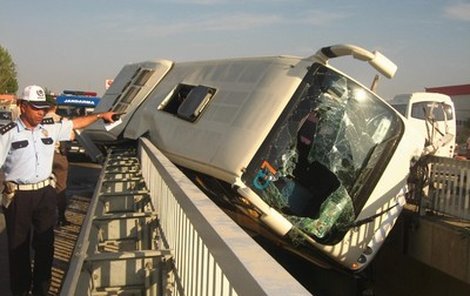 Rozbitý autobus mezi svodidly na mostě.