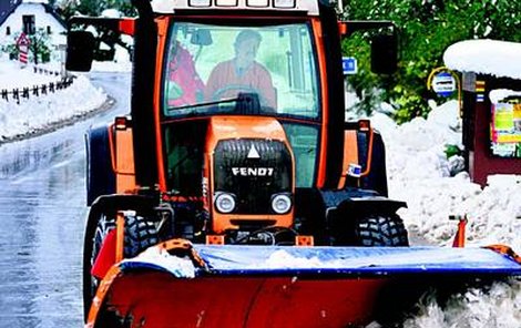 Traktorista s pluhem odhrnuje více než metrové závěje sněhu.