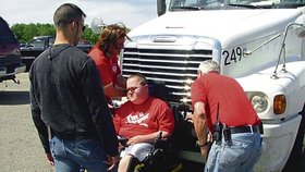 Invalidův vozík se snaží mechanici sundat z čumáku náklaďáku