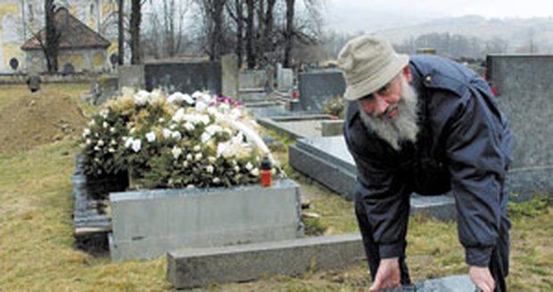 Hrobař Jan Hladík ukazuje trosky náhrobního kamene. Hrob nyní provizorně zakrývá dřevěná deska.