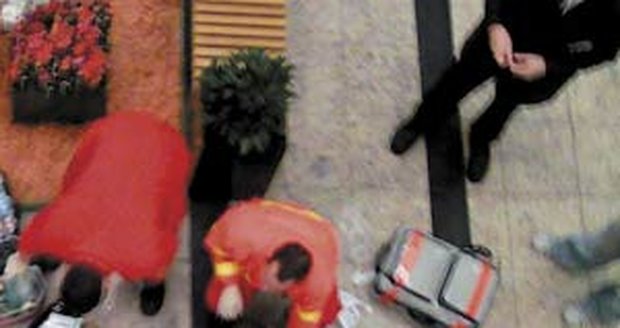 Zraněný muž z Konga
leží bezvládně na
zemi a záchranáři mu
poskytují první pomoc