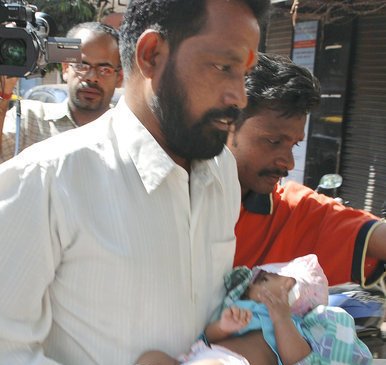 Muž nese dítě, které přežilo řádění teroristů