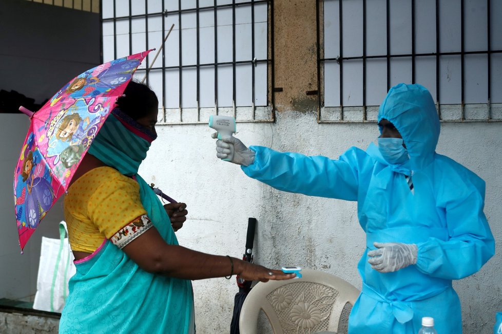Koronavirus v Indii: Zdravotník kontroluje teplotu lidí před vstupem do centra pro nakažené. (25.7.2020)
