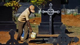 Jeden z pracovníků hřbitova připravuje hrob, do nějž bude rakev uložena
