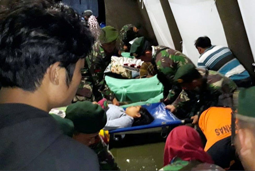 Voják se v polní nemocnici v Lomboku sklání nad ženou zraněnou při zemětřesení v Indonésii.