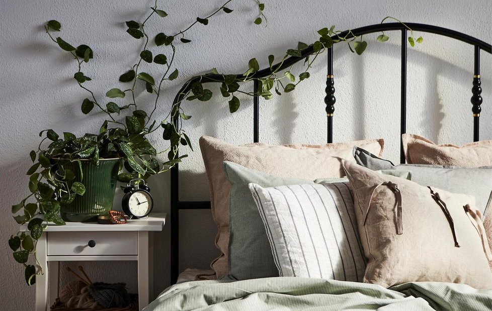 Kontrast bílého dřevěného nočního stolku a černého kovového rámu postele zjemní ložní textil v jemné béžové či zelenkavé.