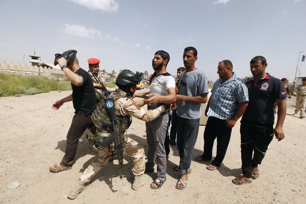 Člen Irácké gardy prohledává kolemjdoucí.