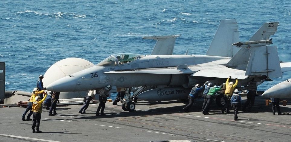 Jedna ze dvou stíhaček F / A-18C Hornet, které bombardovaly pozice radikálů z ISIS se připravuje ke startu z lodi USS George HW Bush v Perském zálivu před úsvitem.