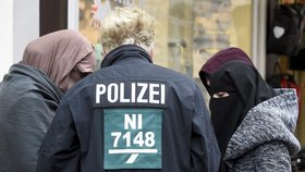 Tři muslimské ženy s policistou před soudem, kde se odehrává proces se Safií S., která se pokusila na povel ISIS zavraždit dva policisty.
