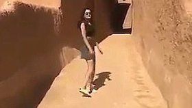 Dívka chodí v krátké sukni a topu po saúdské vesnici.