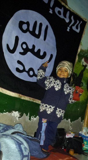 Teprve čtyřletý chlapeček pózuje před vlajkou Islámského státu.