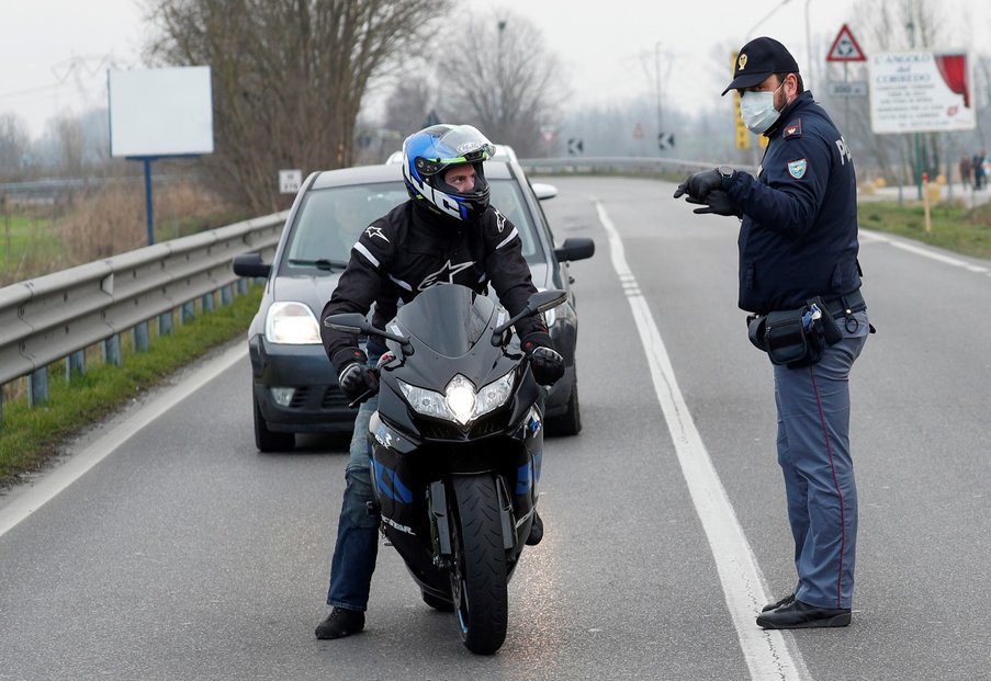 Policista s rouškou oznamuje řidiči uzavírku silnice na severu Itálie kvůli epidemii koronaviru (23. 2. 2020)