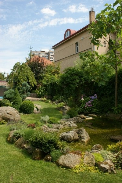 Vodní kaskáda vyvěrá pod terasou s bazénem a v podstatě kopíruje plot porostlý bujnou popínavou zelení