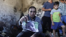 Příbuzný ukazuje foto 18měsíčního Aliho, který uhořel při útoku izraelských radikálů.
