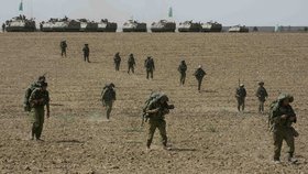 Vojáci Izraele se přemisťují po poli na hranicích s Palestinou.