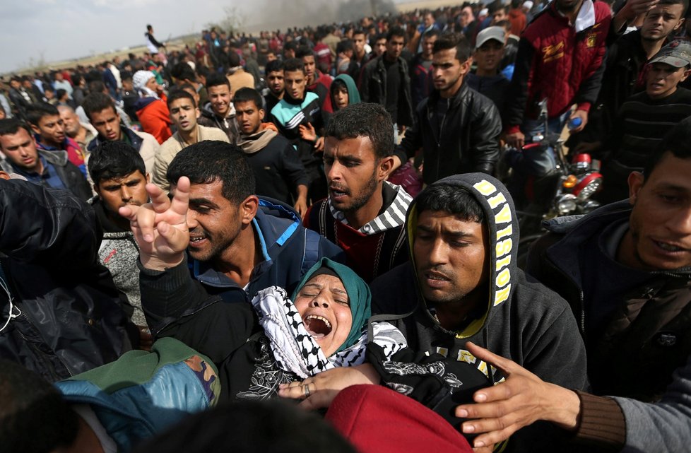 Protestující Palestinci na hranicích Pásma Gazy odnáší zraněnou ženu.