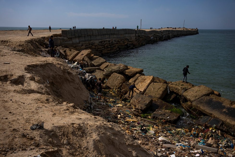 Palestinci vyhlížejí humanitární pomoc na břehu moře.