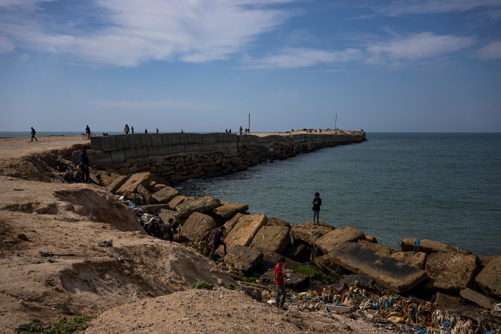 Palestinci vyhlížejí humanitární pomoc na břehu moře.