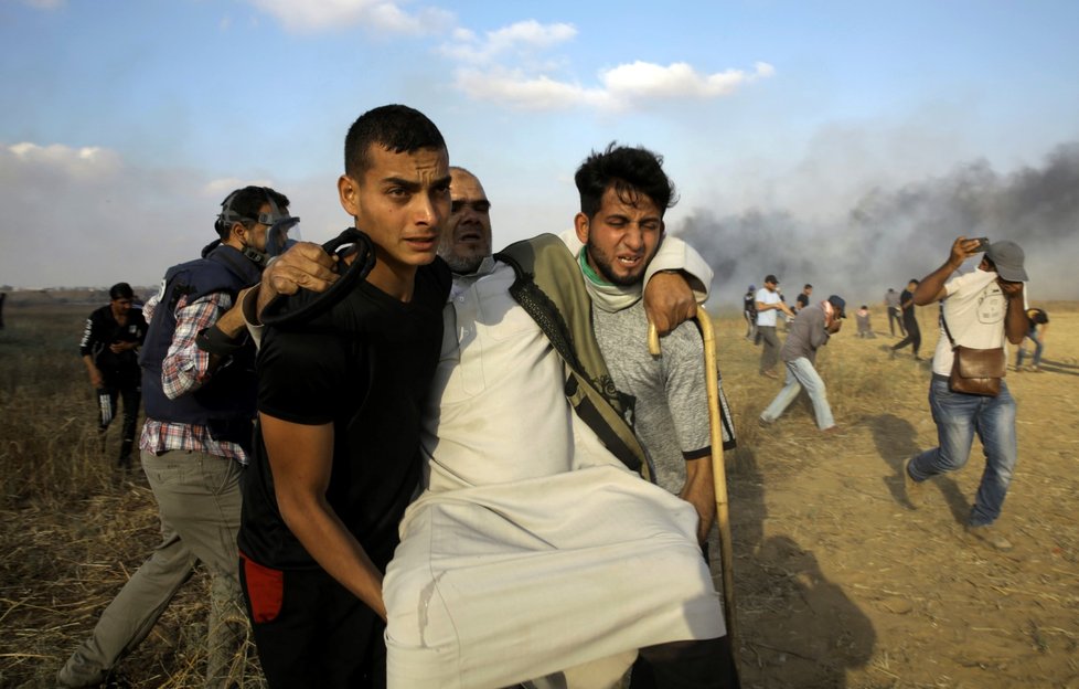 Palestinci u hranic Pásma Gazy odnáší zraněného protestujícího