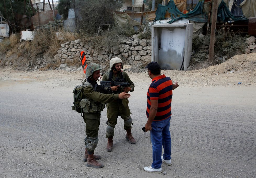 Izraelští vojáci míří na Palestince nedaleko místa, kde se jiný Palestinec pokusil izraelské vojáky přejet bagrem.