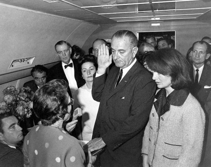 Vicepremiér Lyndon B. Johnson skládá prezidentskou přísahu na palubě Air Force One. Jackie Kennedy přihlíží