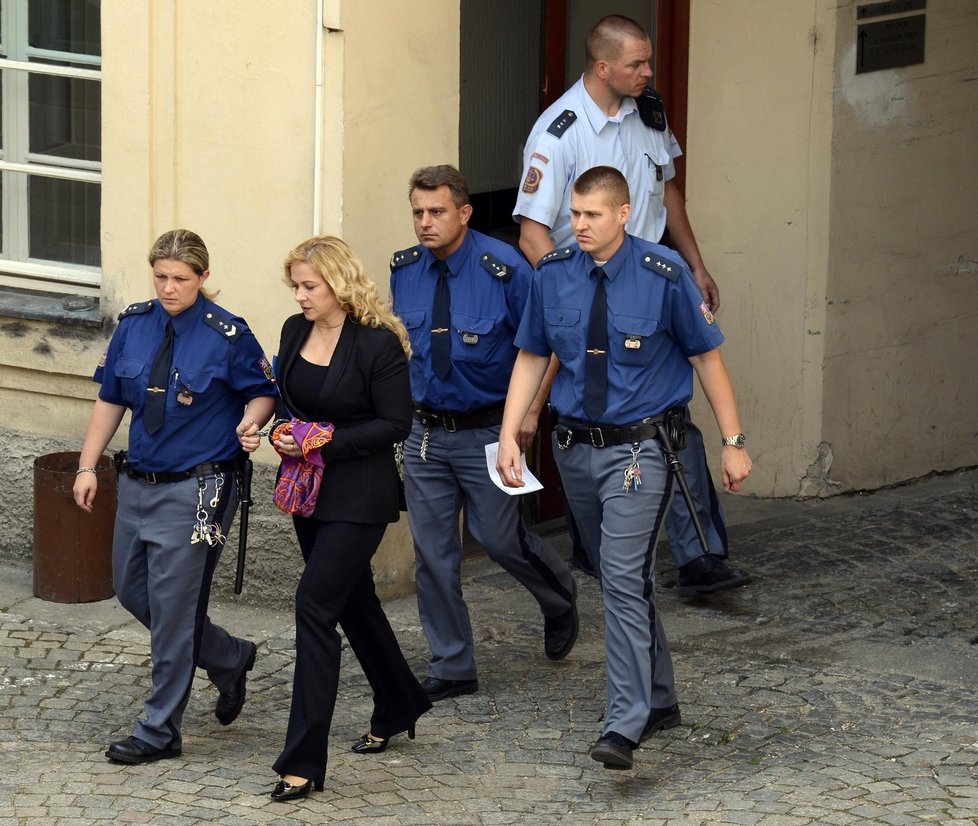 Jana Nagyová dobře zvolila kalhotový kostým. Hedvábný šál pouta navýsost elegantně kryje. Advokát národu sděluje, že zhubnula deset kilo. Vypadá líp i přes znavený výraz tváře, který image ženy, jež pochybila a také posloužila coby kouřová clona, nahrává.